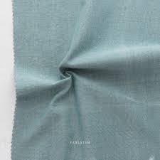 Close-up of light teal fabric with 'Fableism' branding. Cotton Bamboo Blend Chambray