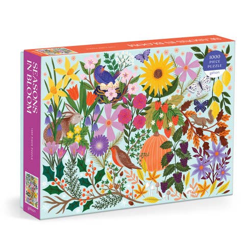 A 1000-piece jigsaw puzzle box titled 'Seasons in Bloom' featuring a colorful, dense illustration of wildflowers, birds, butterflies, and autumn foliage on a white background.