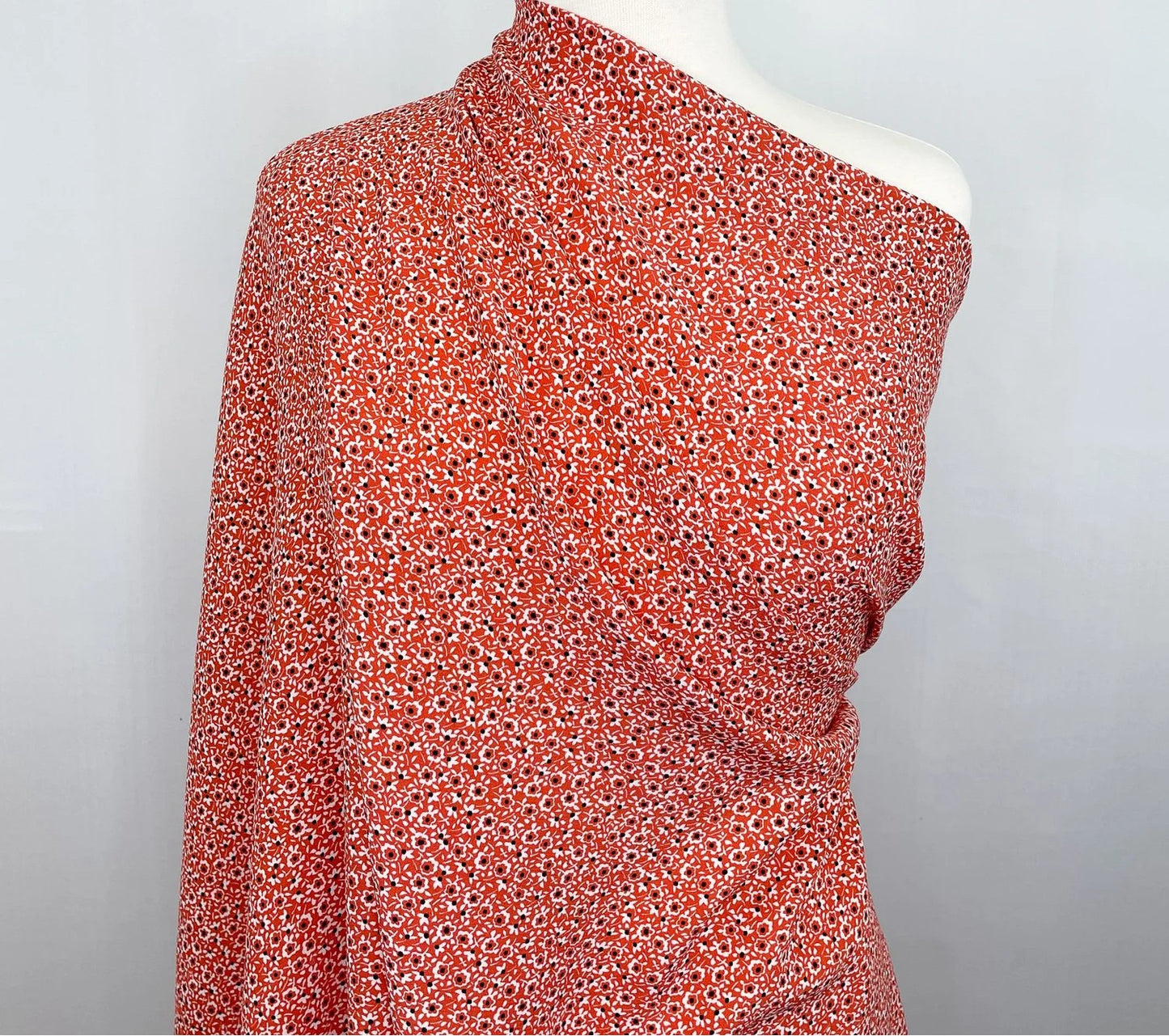 One-shoulder top with red floral pattern fabric on a mannequin against a gray background