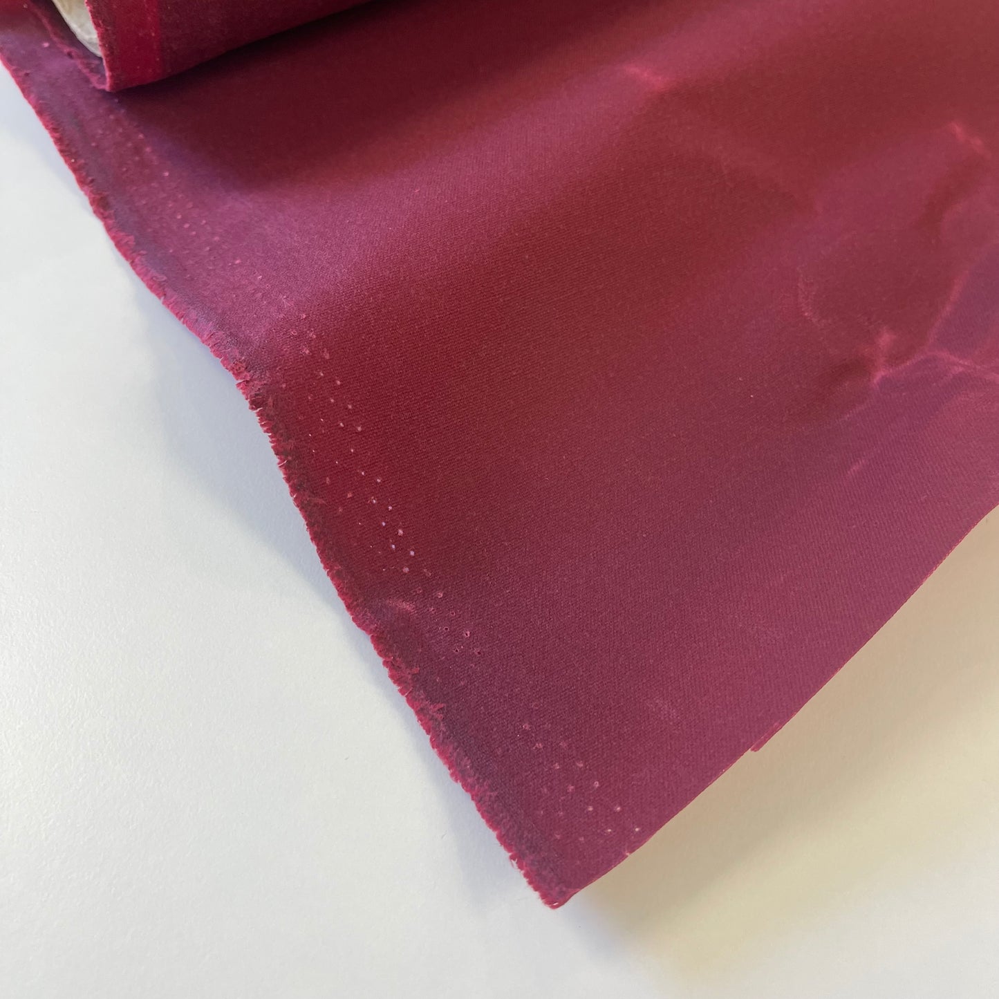 A close-up of dark red waxed canvas fabric material for sewing and crafting and bag making.