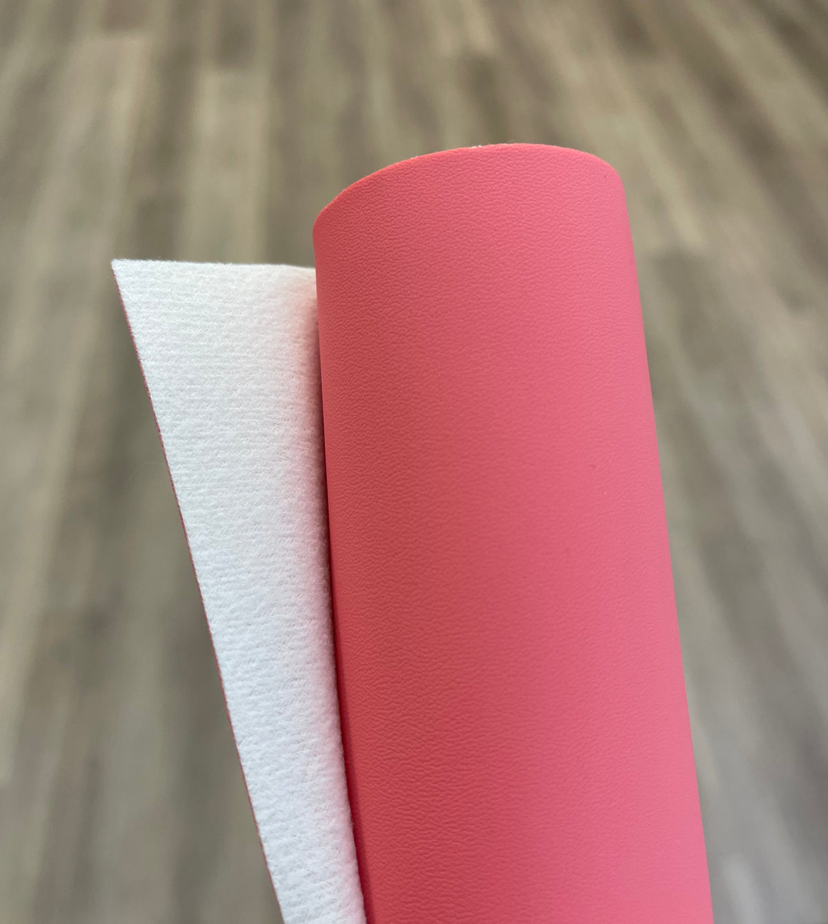 Roll of coral pink faux leather fabric for sewing and crafting.