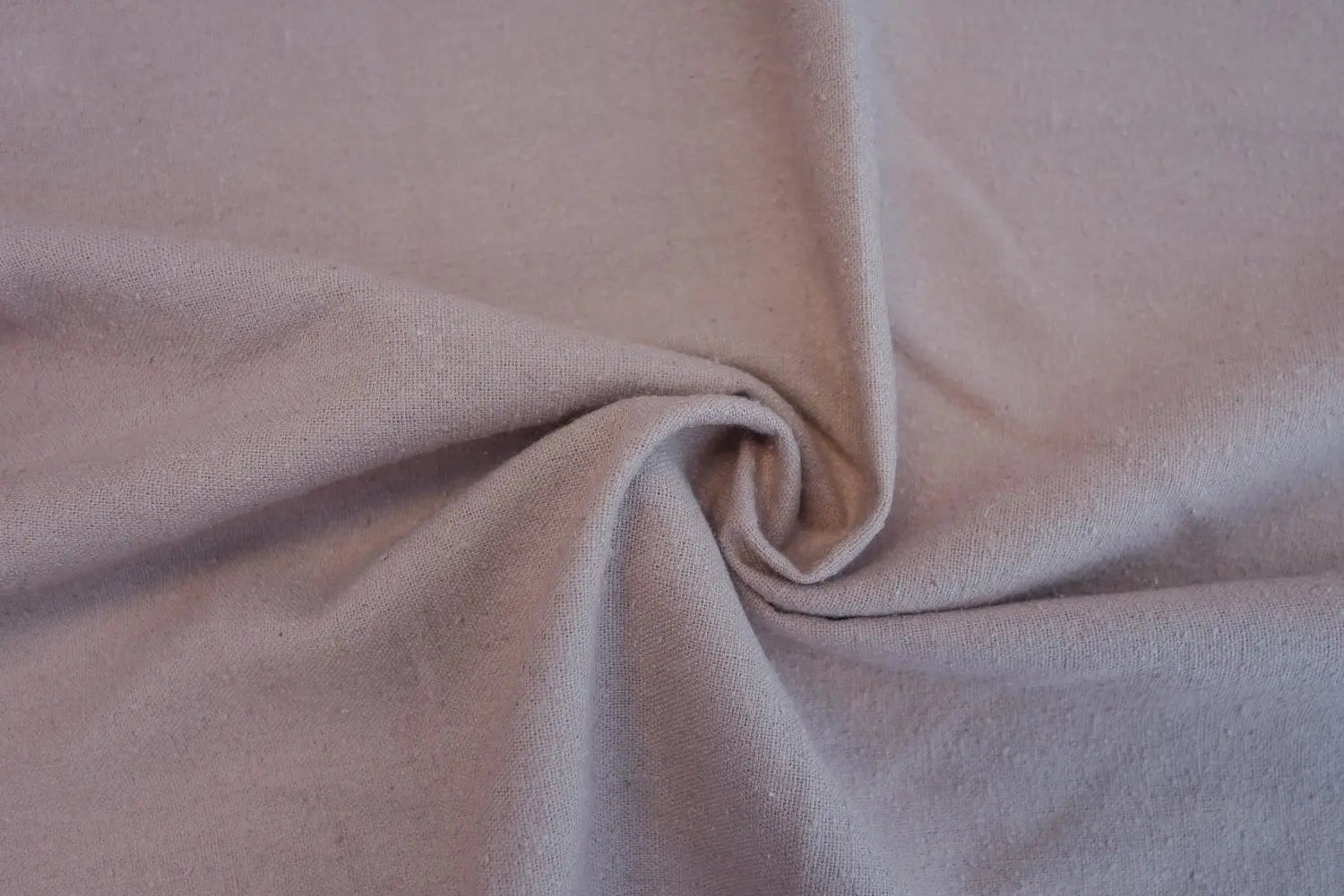 A close up of 100% silk noil (raw silk) fabric in blush pink. 