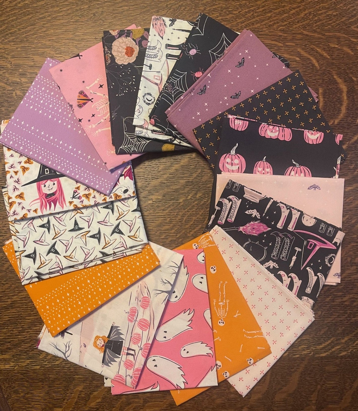 Collection of halloween themed fabric squares on a wooden surface. from art gallery fabrics.