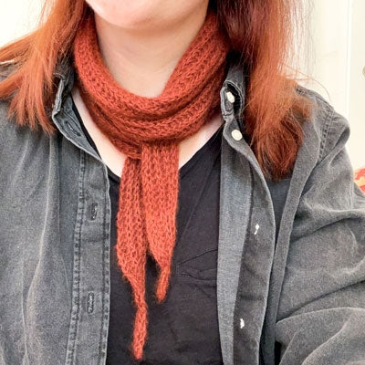 Person wearing a red scarf and gray jacket with a neutral background