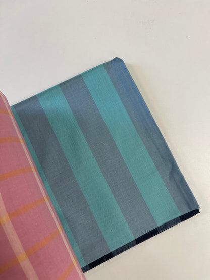 A folded piece of fabric with vertical stripes in teal, blue, and gray, partially overlapping with a pink striped fabric on a plain white surface.