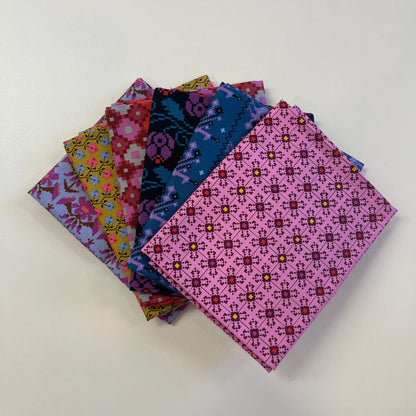 A stack of colorful patterned fabric squares fanned out on a plain white background. The fabrics feature various geometric and floral motifs in pink, blue, purple, yellow, and red.