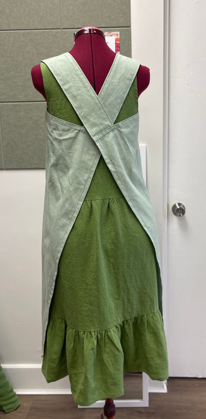 a cross back apron in cotton linen blend displayed on a sewing dummy for sewing lesson and workshop.