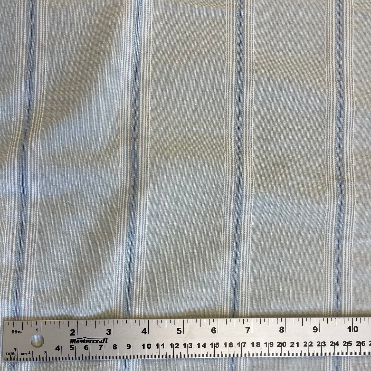 Striped blue cotton fabric with a ruler at the bottom for scale