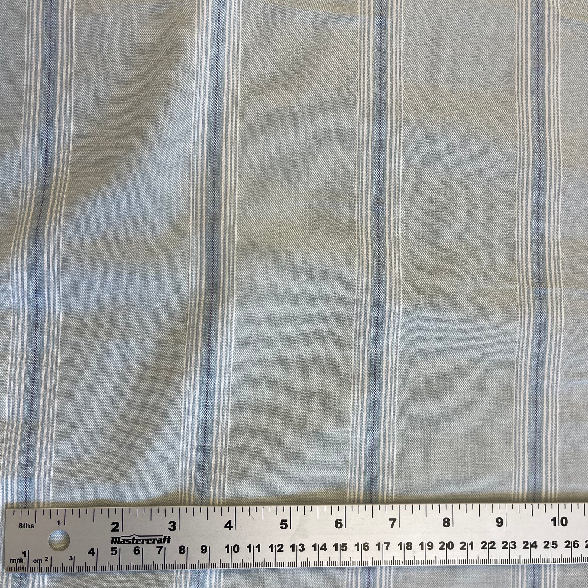 Striped blue cotton fabric with a ruler at the bottom for scale