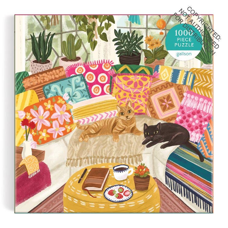 Jigsaw puzzle packaging with a colorful living room scene featuring two cats on a couch.