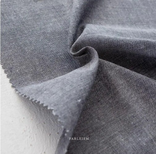 Close-up of medium grey fabric with 'Fableism' branding. Bamboo Cotton blend chambray