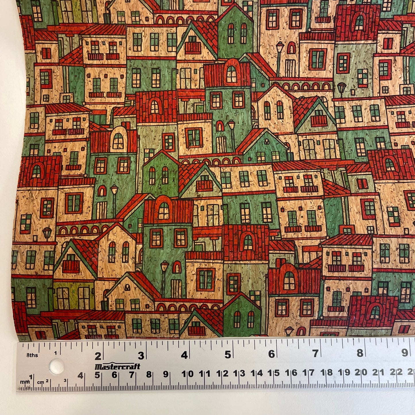 Cork Fabric with a pattern of colorful houses and a ruler at the bottom for scale.