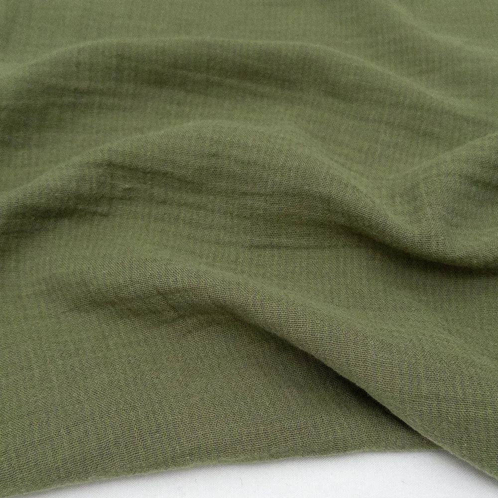 Close-up of green double gauze fabric with a textured striped pattern