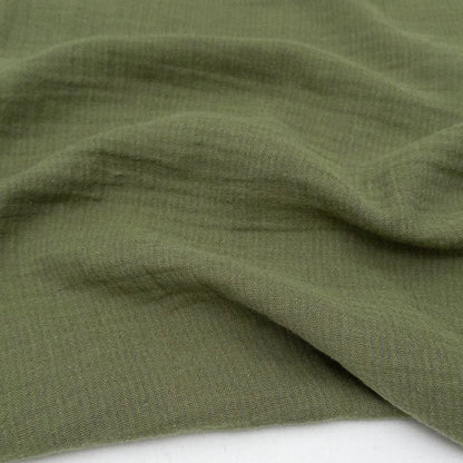 Close-up of green double gauze fabric with a textured striped pattern