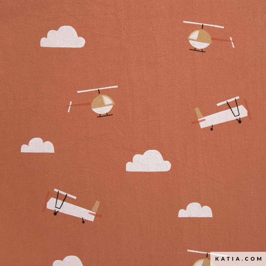 Close up of 100% cotton fabric for sewing children's clothing in orange with planes 