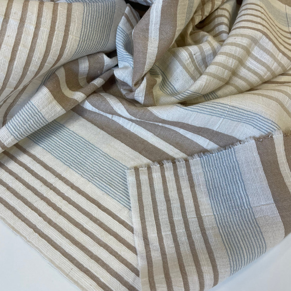 Striped lightweight cotton fabric with brown and beige pattern on a white background for sewing garments