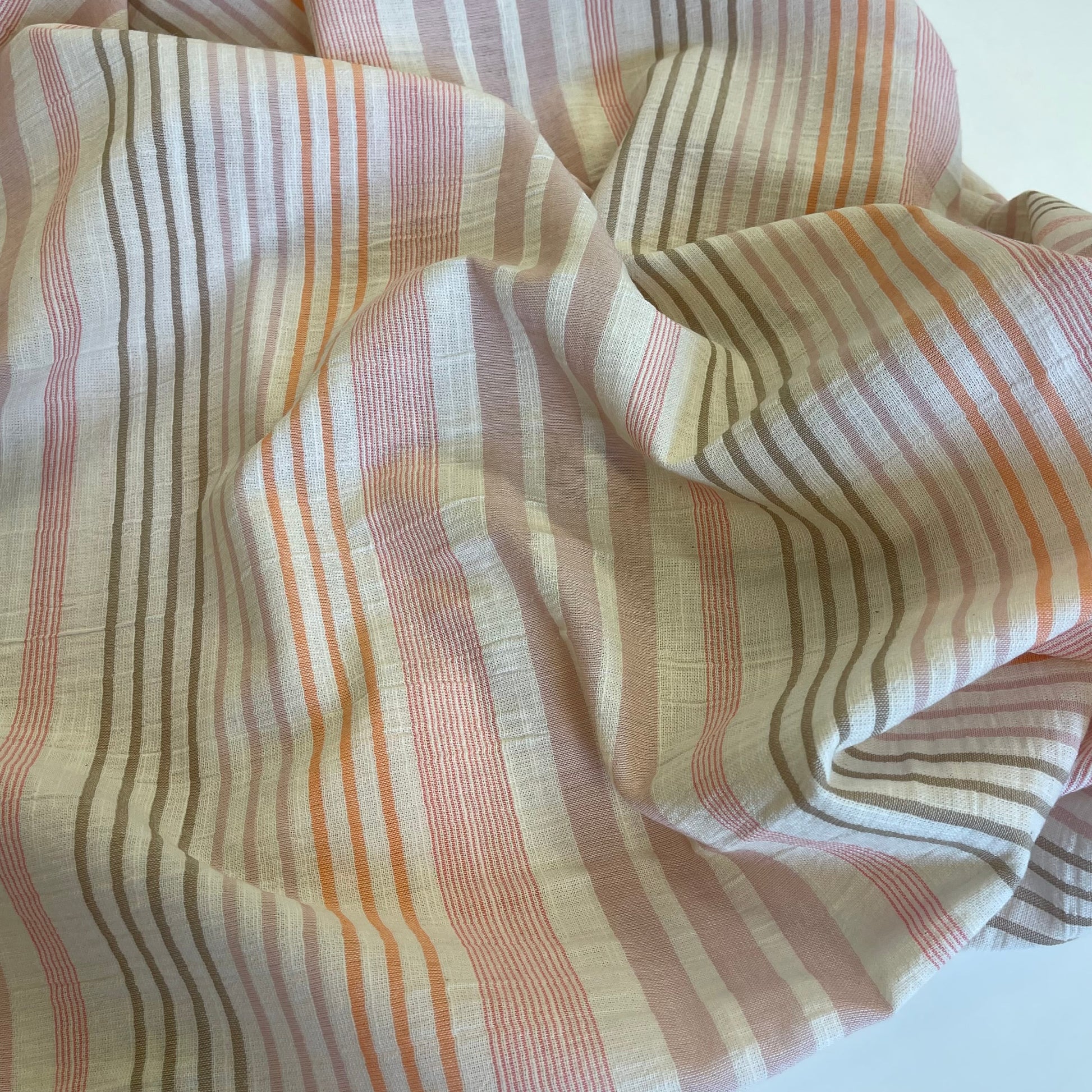 Striped fabric with pink, orange, and beige colors on a white background