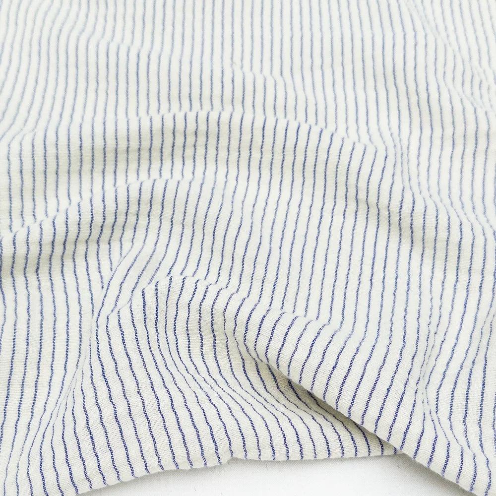Close-up of white cotton organic fabric with blue stripes for sewing and crafting. 