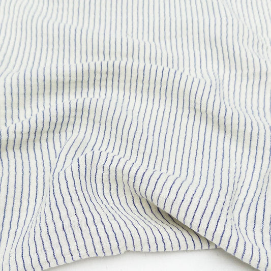 Close-up of white cotton organic fabric with blue stripes for sewing and crafting. 