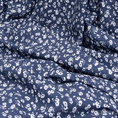 Blue organic cotton fabric with small white floral pattern for sewing and crafting
