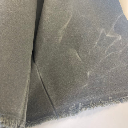 A roll of dark medium waxed canvas fabric with a frayed edge, partially unrolled on a plain white background.