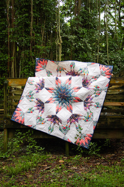 Quilt with floral pattern draped over a wooden bench outdoors