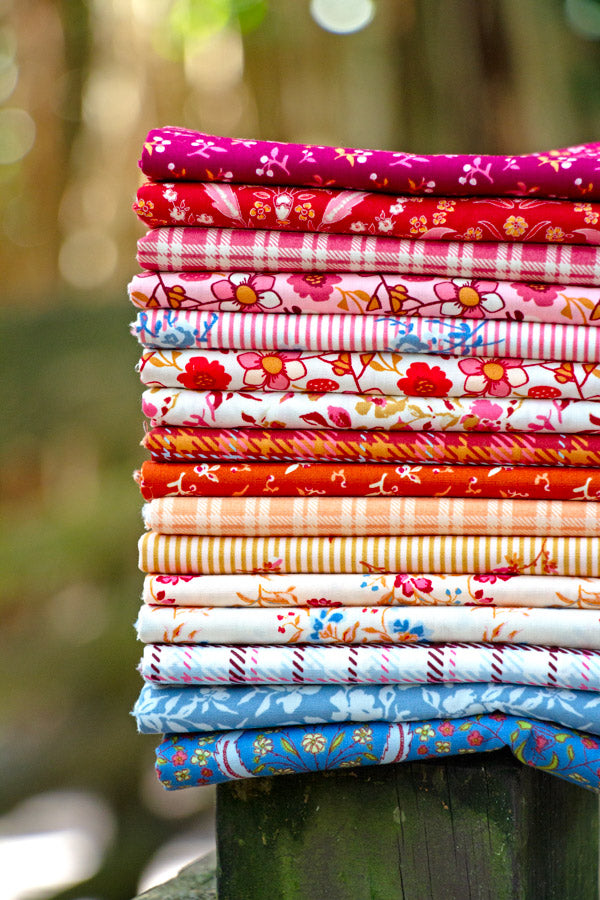 Stack of colorful fabric rolls with a blurred natural background from Fairview avenue Bari J Art Gallery Fabrics quilting cotton for sewing and crafting.