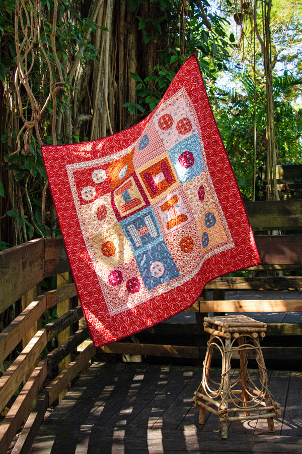 Colorful quilt with geometric patterns draped over a wooden bench outdoors from Fairview avenue Bari J Art Gallery Fabrics quilting cotton for sewing and crafting.
