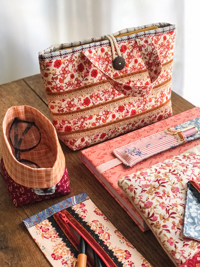 Floral-patterned bags and accessories on a wooden surface from Fairview avenue Bari J Art Gallery Fabrics quilting cotton for sewing and crafting.