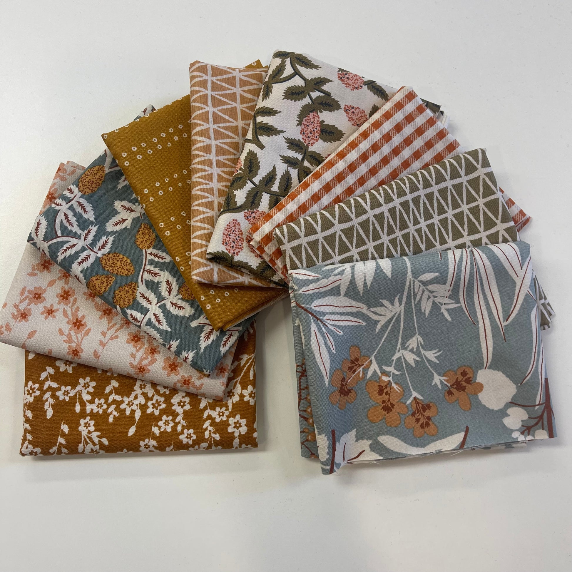 Collection of patterned fabric swatches on a white background for sewing and quilting. 