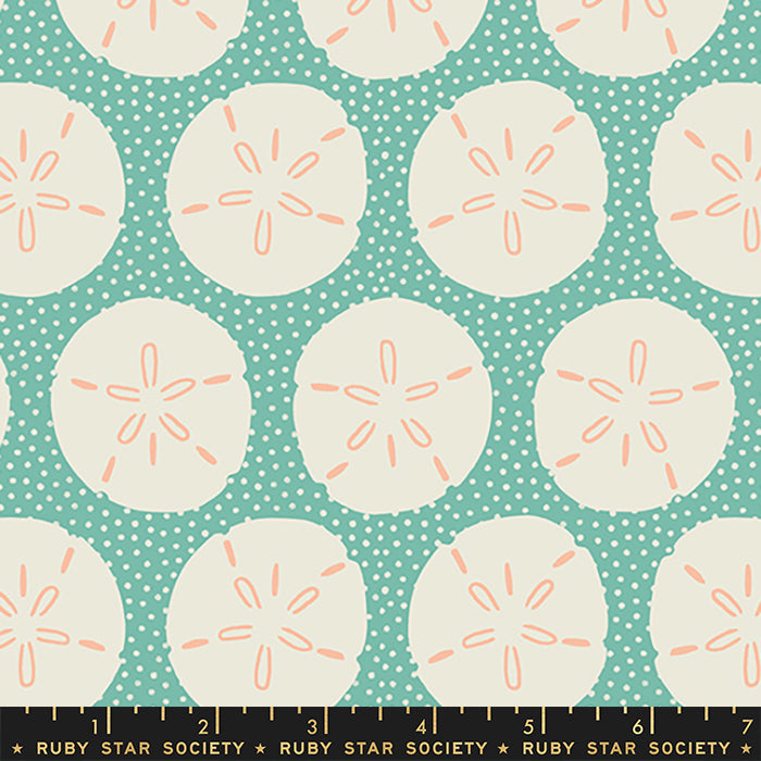 A repeating fabric pattern featuring cream sand dollars on a teal polka-dot background, with a Ruby Star Society ruler along the bottom edge.