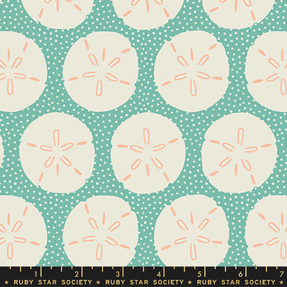 A repeating fabric pattern featuring cream sand dollars on a teal polka-dot background, with a Ruby Star Society ruler along the bottom edge.