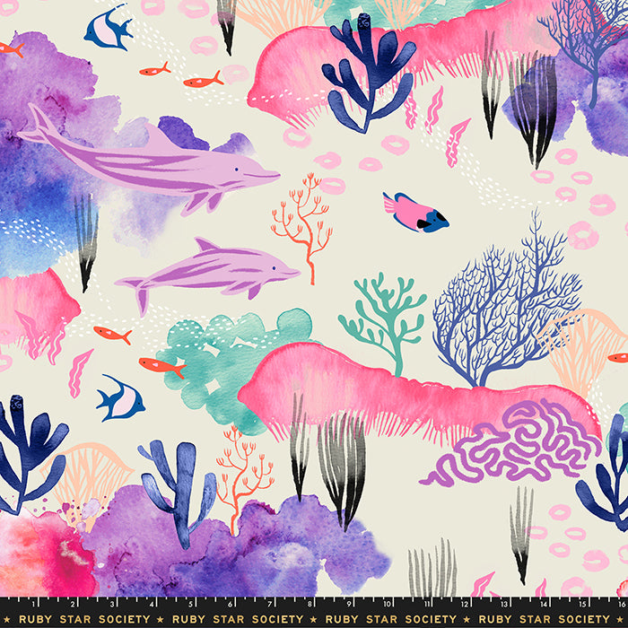 Fabric with a repeating watercolor-style underwater pattern with pink coral, purple dolphins, blue and teal sea plants, small orange fish, and a cream background. A black strip at the bottom reads RUBY STAR SOCIETY with ruler markings, indicating this is likely fabric or a print sample.