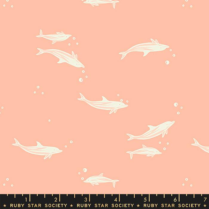 A repeating pattern of white dolphins swimming on a peach-pink background, with small white bubbles and a black ruler strip at the bottom labeled Ruby Star Society.