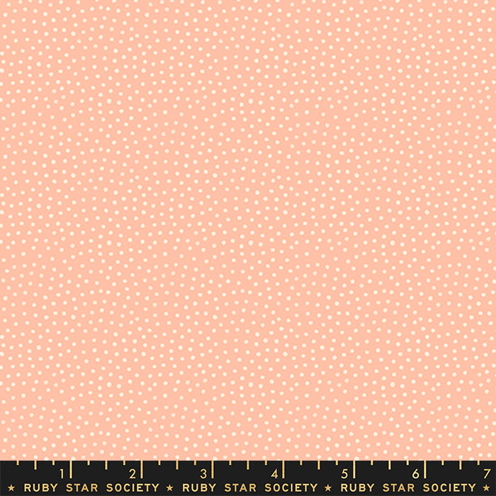 A close-up fabric pattern swatch showing a light peach background with a dense pattern of small white polka dots. A black ruler with gold markings and the brand name 'RUBY STAR SOCIETY' is visible along the bottom edge.