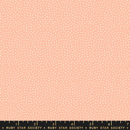 A close-up fabric pattern swatch showing a light peach background with a dense pattern of small white polka dots. A black ruler with gold markings and the brand name 'RUBY STAR SOCIETY' is visible along the bottom edge.