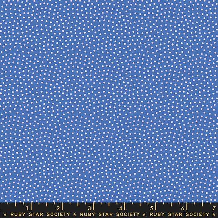 A close-up of blue fabric with a repeating pattern of small white dots, with a black ruler along the bottom edge labeled Ruby Star Society.