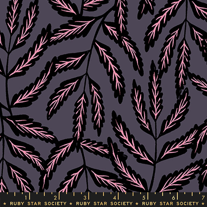 A close-up of a fabric pattern featuring stylized pink leaves on black stems against a dark charcoal gray background, with a Ruby Star Society ruler visible along the bottom edge.