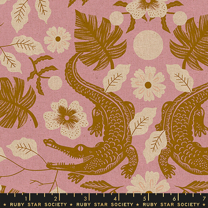 A close-up of a fabric pattern featuring brown alligators and tropical leaves on a dusty pink background, with a black ruler strip at the bottom showing the scale of the print. The text 'RUBY STAR SOCIETY' is visible on the ruler.