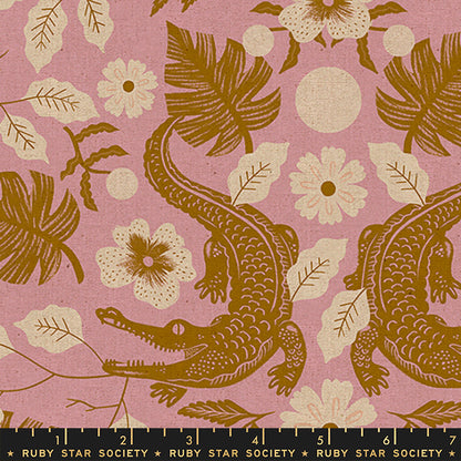 A close-up of a fabric pattern featuring brown alligators and tropical leaves on a dusty pink background, with a black ruler strip at the bottom showing the scale of the print. The text 'RUBY STAR SOCIETY' is visible on the ruler.