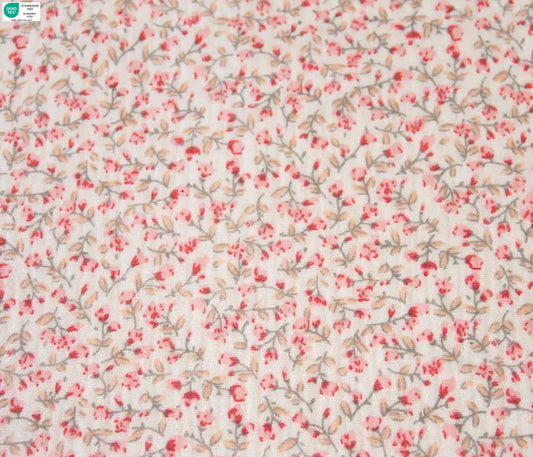 Floral patterned fabric with small pink flowers and green leaves on a light background cotton fabric for sewing.