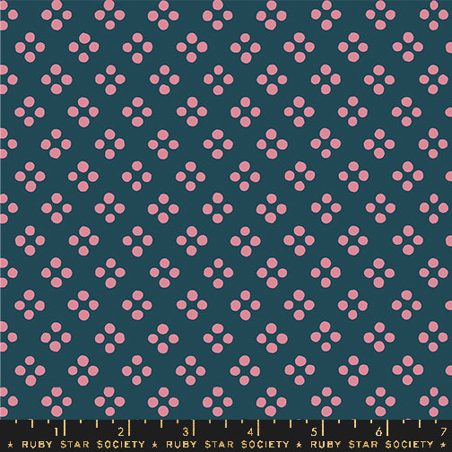 A repeating fabric pattern featuring small pink dots arranged in small clusters on a dark teal background, with a Ruby Star Society ruler along the bottom edge for scale.