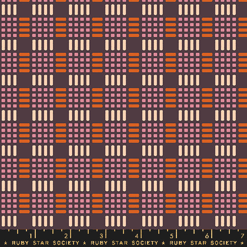 Fabric with a repeating retro geometric pattern featuring orange, dusty pink, and cream blocks on a dark plum background, with a black ruler strip at the bottom labeled Ruby Star Society.