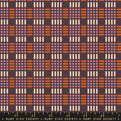 Fabric with a repeating retro geometric pattern featuring orange, dusty pink, and cream blocks on a dark plum background, with a black ruler strip at the bottom labeled Ruby Star Society.