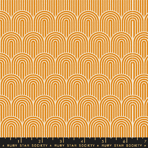 A repeating fabric pattern featuring orange and white concentric arches in a retro mid-century modern design, with a black ruler at the bottom showing the scale of the pattern.