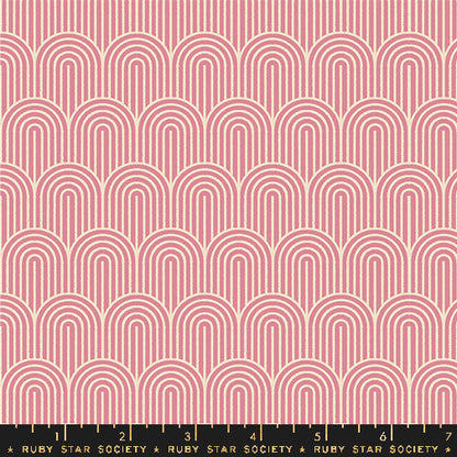 A repeating fabric pattern featuring pink and cream arches in a retro, geometric design, with a black measuring ruler at the bottom showing the scale of the pattern.
