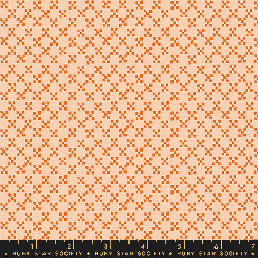 A repeating fabric pattern featuring orange geometric diamond and square motifs on a light peach background, with a black ruler at the bottom displaying the Ruby Star Society brand and measurements.
