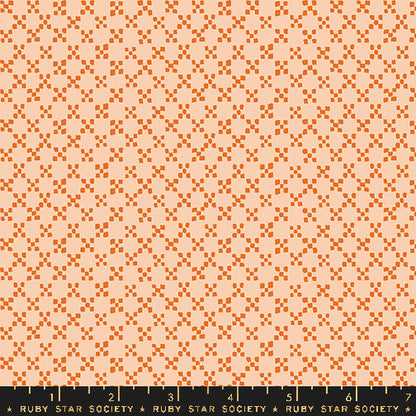 A repeating fabric pattern featuring orange geometric diamond and square motifs on a light peach background, with a black ruler at the bottom displaying the Ruby Star Society brand and measurements.