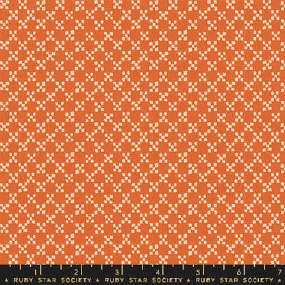 A close-up of a repeating geometric fabric pattern in orange and cream, with a black ruler along the bottom edge labeled Ruby Star Society.