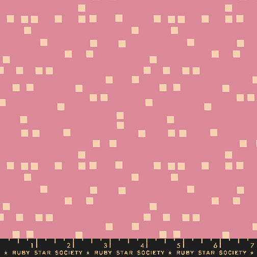 A pink fabric or material swatch with a repeating pattern of small pale cream squares, plus a black ruler strip along the bottom edge labeled Ruby Star Society.